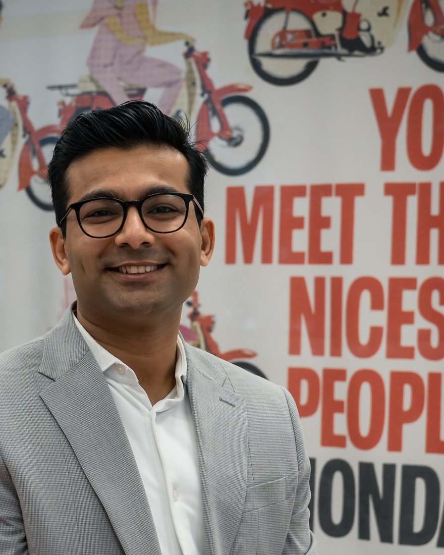 Mandar Bhoyar, standing in front of a vintage Honda advertising poster reading “You meet the nicest people on a Honda”